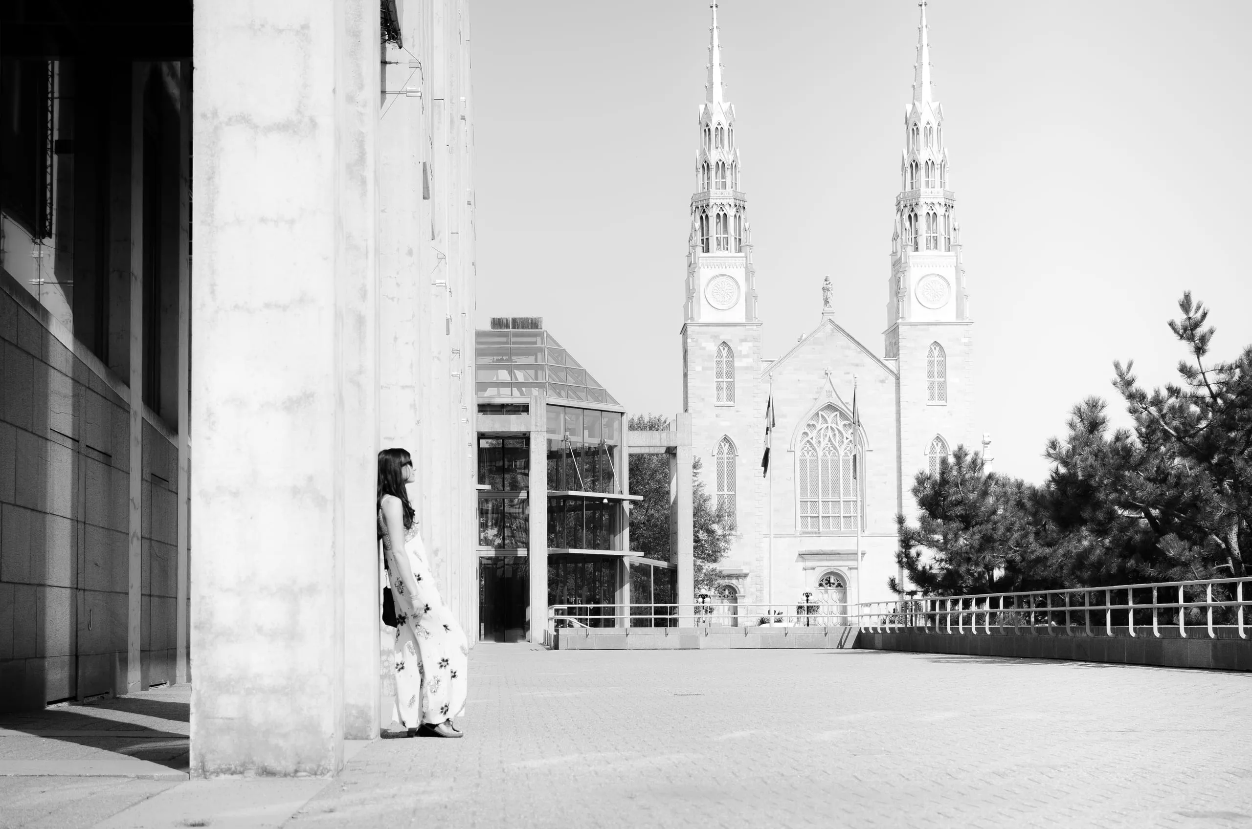 Black and white view of Notre-Dame Basilica spires with a figure in a patterned dress in the foreground, Ottawa
